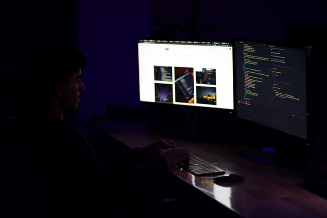 A man in a dark room programming at his desk