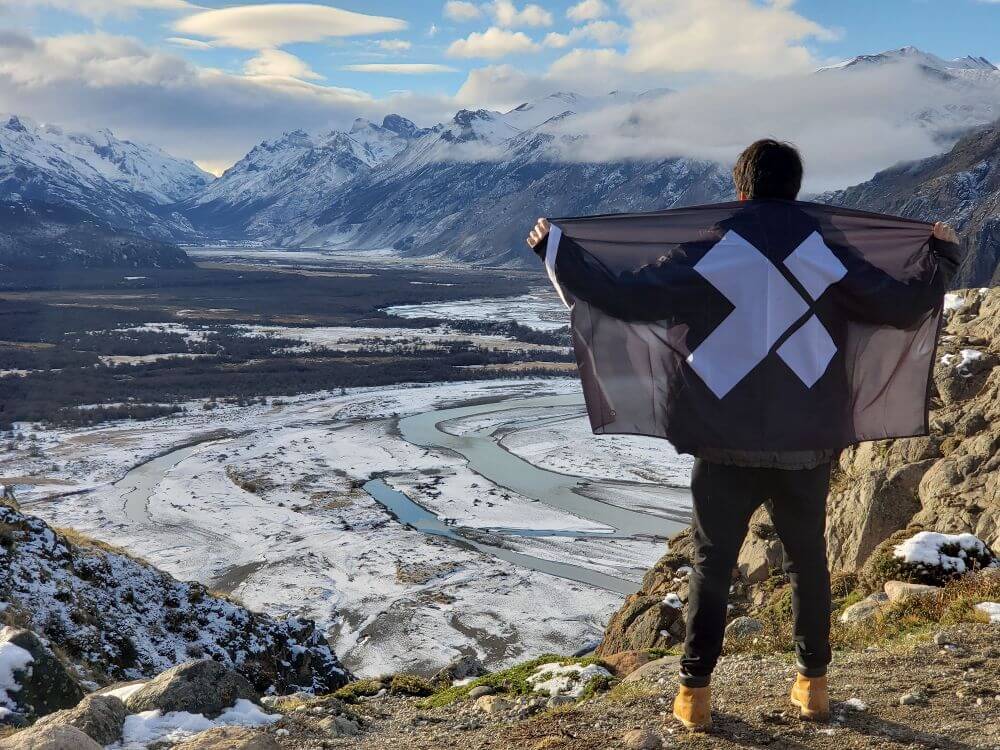 A man holding an X-Team flag looking over mountains