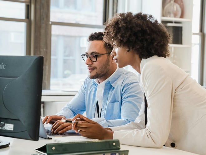 Two people behind a computer screen