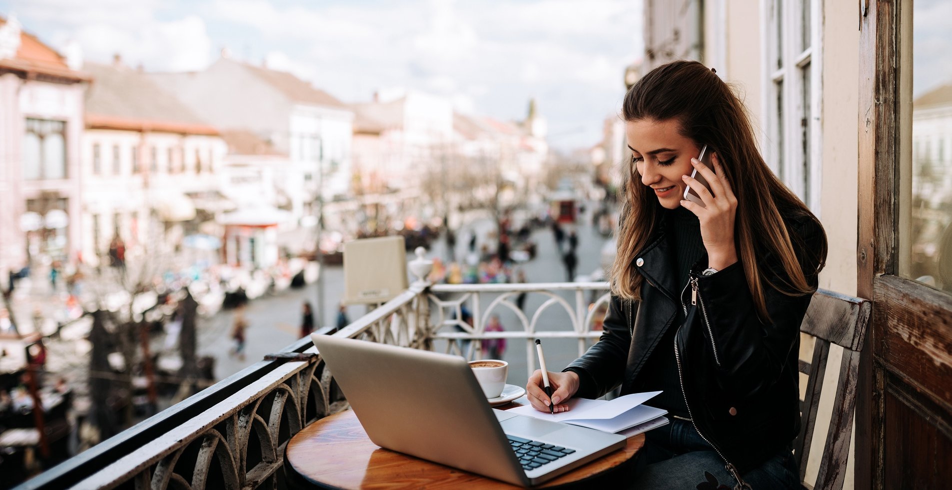 A woman on a computer, working on a balcony