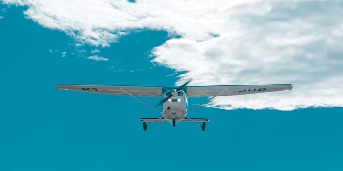 A small plane against a blue, cloudy sky