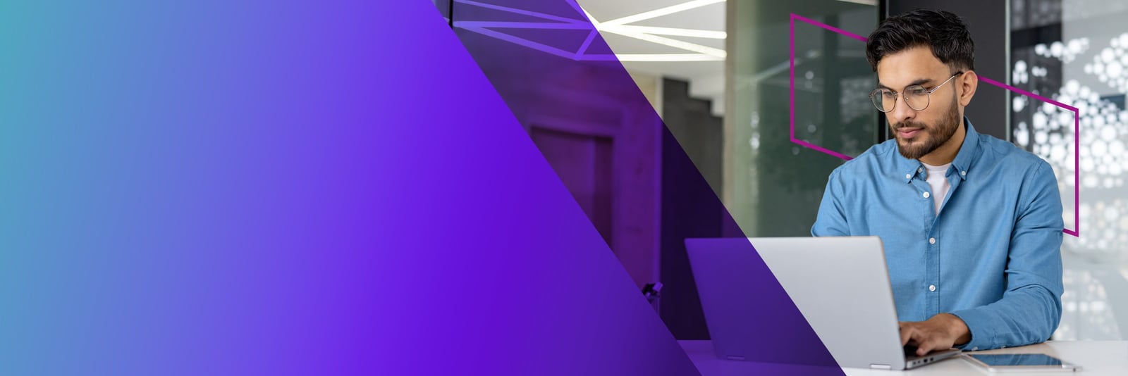 Developer focused on a laptop in a modern glass-walled office