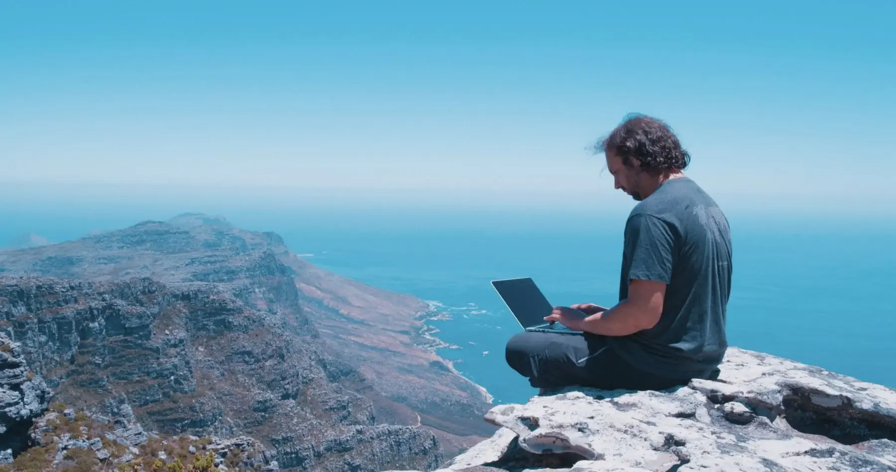 Man working on a cliff overlooking mountains