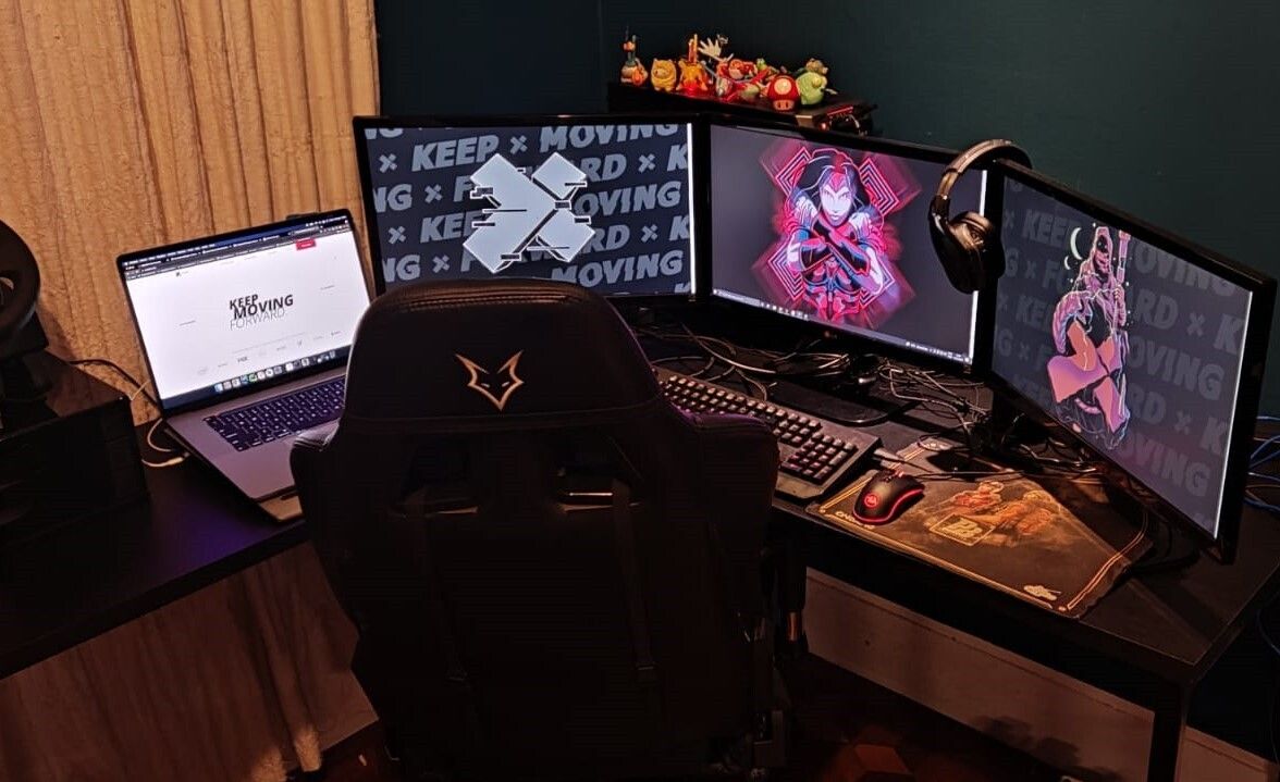 An X-Teamer's battlestation — triple monitors with Keep Moving Forward wallpaper and the X-Team mark